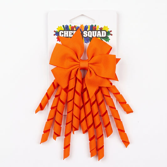 Orange grosgrain korker hair bow with spiral ribbon tails on card